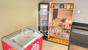 A vending machine with beverages, a refrigerator, and shelves stocked with snacks and candies. - Max Carneiros Suites - Praia dos Carneiros by CTA (Tamandaré)