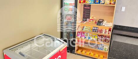 A vending machine with beverages, a refrigerator, and shelves stocked with snacks and candies.