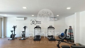 A gym with stationary bikes, a treadmill, and weightlifting equipment. - Max Carneiros Suites - Praia dos Carneiros by CTA (Tamandaré)