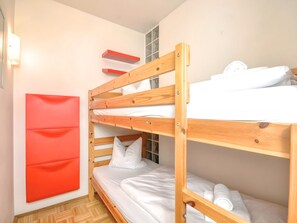 A bunk bed room with a red wall, wooden bunk beds, and a window with curtains. - 2_Fürth_11 Kitzsteinhorn Kaprun Panorama by Interhome (Kaprun)