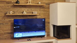 A television mounted on a wooden wall with a fireplace below. - 2_10 KitzNest Kaprun by Interhome (Kaprun)