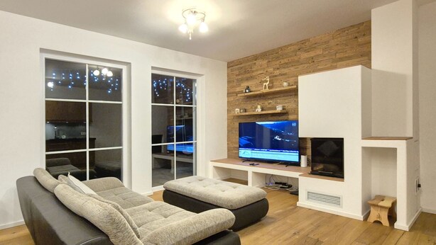 A modern living room with a sofa, TV, and wooden flooring. - 2_10 KitzNest Kaprun by Interhome (Kaprun)