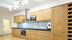 A modern kitchen with wooden cabinets, a built-in oven, and a wine rack. - 2_10 KitzNest Kaprun by Interhome (Kaprun)