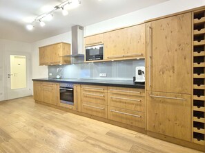 Eine moderne Küche mit Holzausstattung, integriertem Backofen und Weinkühler.