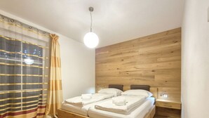 A wooden bed with a headboard, a bedside table, and a wall-mounted light fixture. - 2_10 KitzNest Kaprun by Interhome (Kaprun)