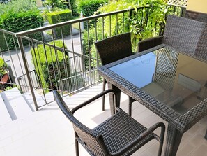 A balcony with wicker furniture and a glass table, overlooking a garden. - I Vigneti del Garda by Interhome (Lazise)