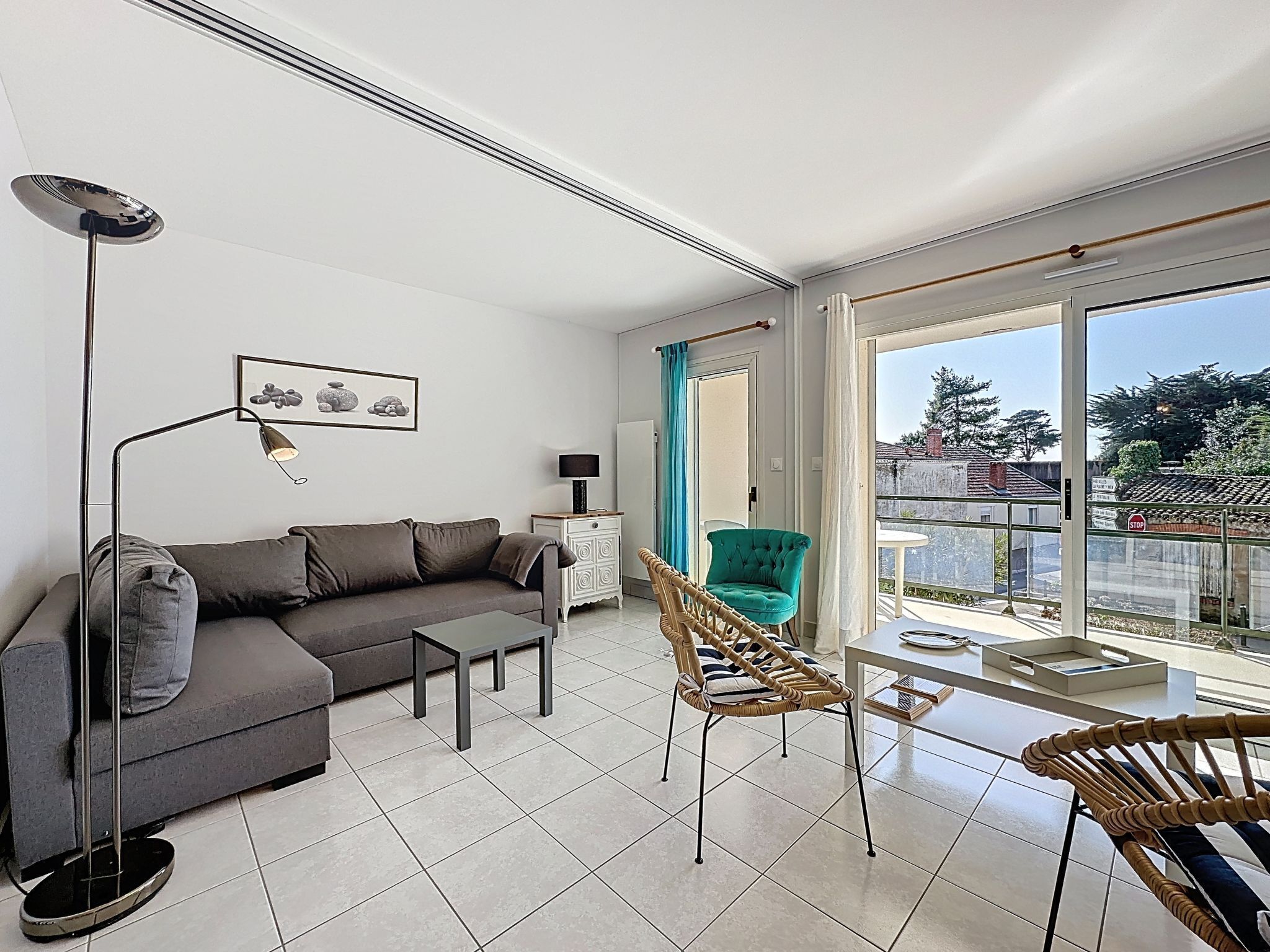 A modern living room with a sofa, coffee table, and chairs, a floor lamp, a side table, and a large window with a view.