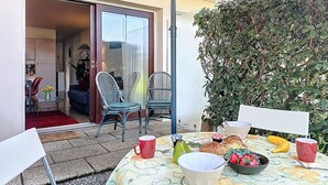 Un espace de restauration en plein air avec une table dressée pour le petit-déjeuner, des chaises et un grand parasol.