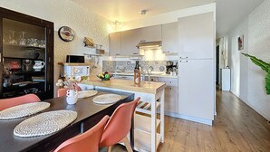 Une cuisine moderne avec un coin repas, comprenant une table en bois, des chaises et un îlot de cuisine.