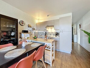Eine moderne Küche mit Essbereich, ausgestattet mit einem Holztisch, Stühlen und einer Kücheninsel.