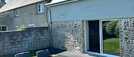 Una casa de piedra con un patio amoblado y un amplio ventanal corredero.