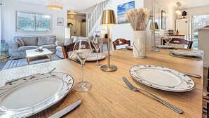 Un'area pranzo con un tavolo di legno apparecchiato per quattro persone, un divano e una scala che conduce a un altro piano.