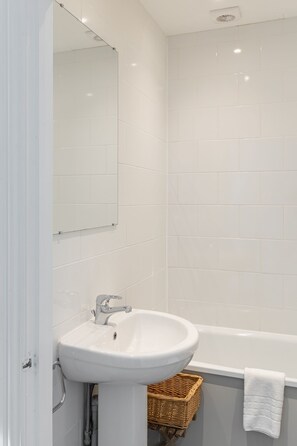 Ein Badezimmer mit Waschbecken, Spiegel und Badewanne.