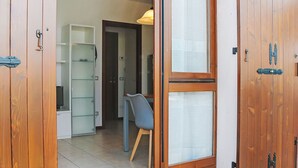 Una habitación con puerta de madera, una silla y una estantería.