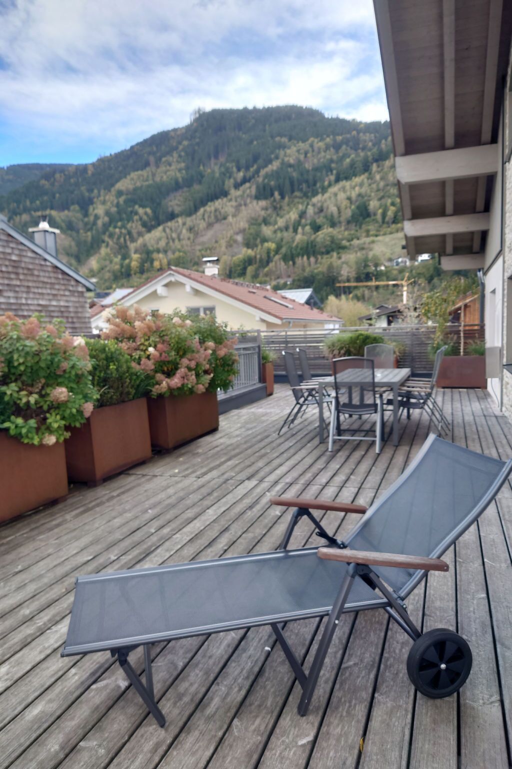 A wooden deck with a table and chairs, overlooking a mountainous landscape.