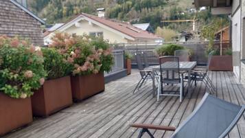 A wooden deck with a table and chairs, overlooking a mountainous landscape.