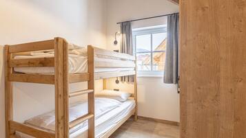 Ein Schlafraum mit Etagenbetten, Fenster, Holzwänden und einem hellen Boden.