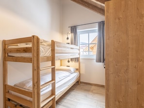 Ein Schlafraum mit Etagenbetten, Fenster, Holzwänden und einem hellen Boden.