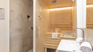 Ein modernes Badezimmer mit Holzvertäfelung, einer Duschkabine aus Glas und einem weißen Waschbecken mit Handtuch.