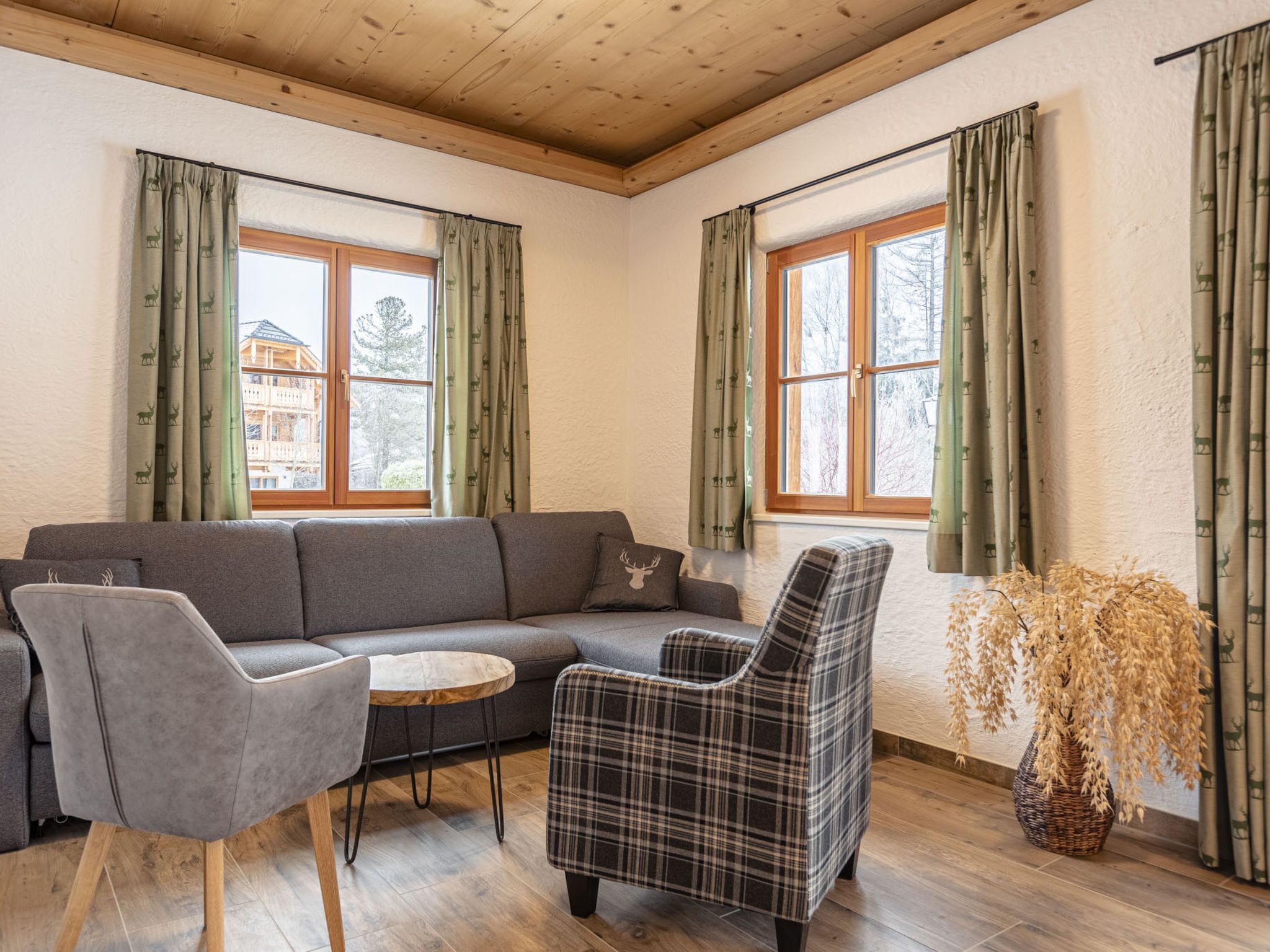 Ein Zimmer mit einer Couch, zwei Sesseln, einem kleinen Tisch und einer Zierpflanze.