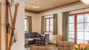 Ein gemütliches Wohnzimmer mit einer Couch, zwei Sesseln, einem Holztisch und einer Blumenvase.
