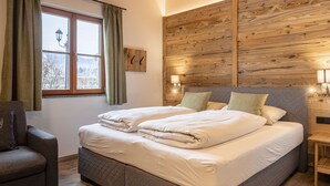 Ein Schlafzimmer mit einem großen Bett, einem Vorhangfenster, einer Wandlampe und einem Holzkopfteil.
