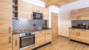 Eine moderne Küche mit Holzschränken, einer strukturierten Spritzschutzwand und einem eingebauten Backofen.