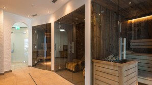A modern interior with glass doors, a wooden reception desk, and a stone wall. - 3_SPA Panorama MAX 205 by Interhome (Zell am See)