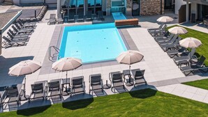 A modern building with a swimming pool, lounge chairs, and umbrellas. - 3_SPA Panorama MAX 205 by Interhome (Zell am See)