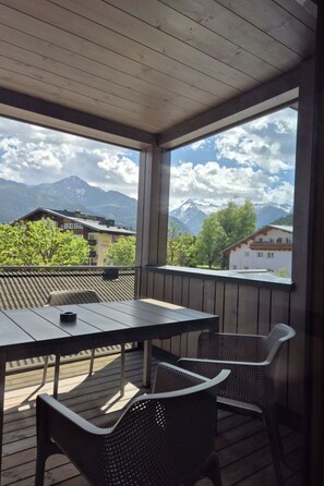 A covered outdoor area with a table and chairs, overlooking a mountainous landscape. - 3_SPA  Panorama MAX 205 by Interhome (Zell am See)