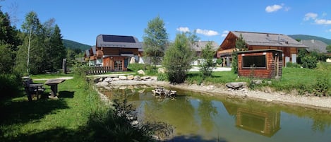 Una cabaña junto al lago con comedor y un pequeño estanque.