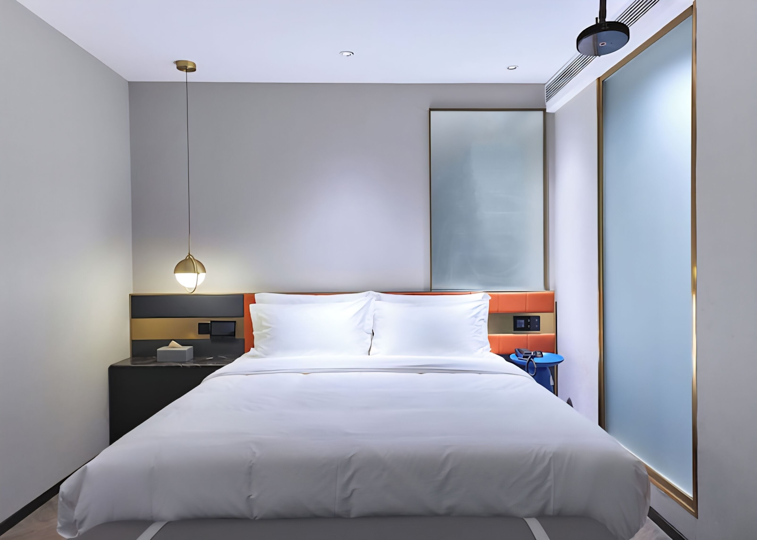 A modern hotel room with a large bed, a bedside table, a nightstand, a wall-mounted TV, and a large window.