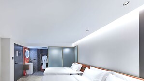 A modern hotel room with two beds, a bathroom with a mirror, and a robe hanging on the door. - Life Style  (Douala)