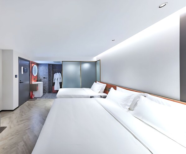 Una habitación de hotel moderna con dos camas, un baño con espejo y una bata colgada en la puerta.