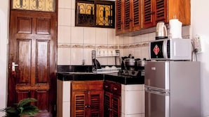Cozinha com armários de madeira, geladeira de aço inoxidável, micro-ondas e cafeteira.