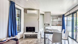 Una sala de estar moderna con un televisor de pantalla plana, una mesa de comedor y sillas.