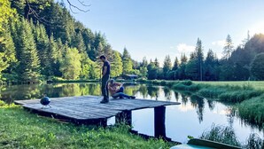 Un muelle de madera se adentra en un lago tranquilo rodeado de un bosque frondoso.