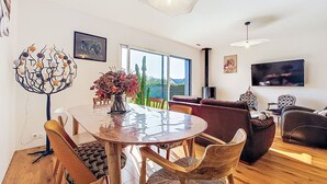 Un salon moderne avec une table à manger ronde, des chaises en bois, un canapé et un téléviseur.