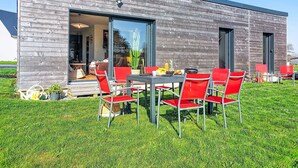 Un bâtiment moderne doté d’un espace repas avec des chaises rouges et une table où sont disposés des plats et des boissons.