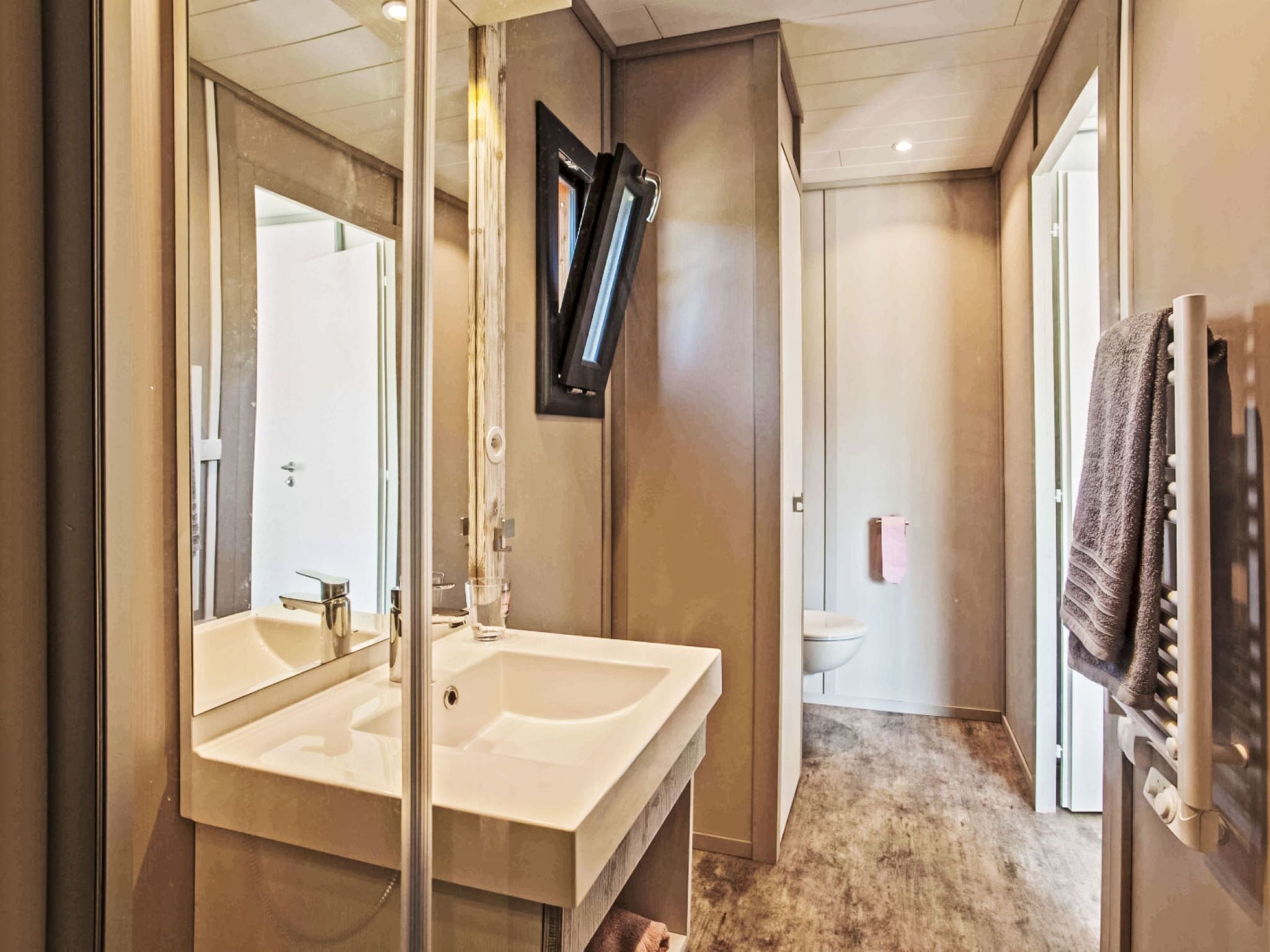 A bathroom with a large mirror, a sink, and a toilet.
