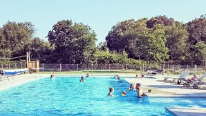 Ein Schwimmbecken mit Personen, Liegestühlen und einer Holzterrasse.