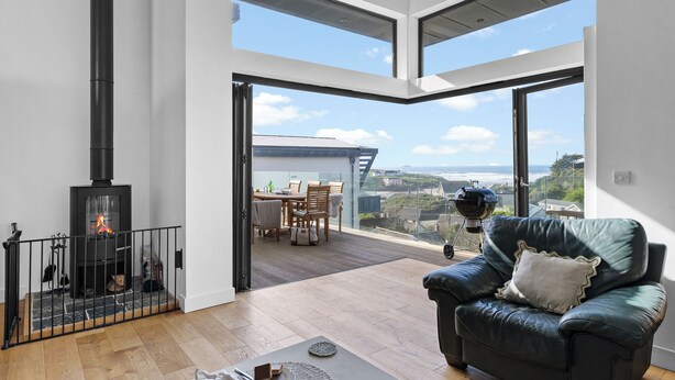 Uma sala de estar moderna com lareira, um sofá de couro e uma área de jantar com vista.