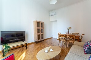 A living room with a flat-screen TV, wooden cabinet, dining table with chairs, and a sofa. - iFlat | Classic roman palazzo Fons Trevi A15 (Rome)