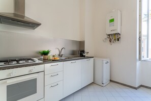 A modern kitchen with white cabinets, a gas stove, a sink, and a built-in dishwasher. - iFlat | Classic roman palazzo Fons Trevi A15 (Rome)