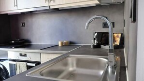 A modern kitchen with a stainless steel sink, a stove, and light-colored cabinets.