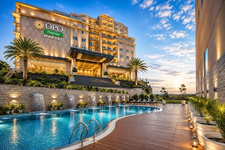 A hotel with a swimming pool, outdoor staircase, and a view of the city.