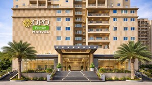 A multi-story hotel with a prominent entrance, palm trees, and a checkered facade. - OPO Premier MARVEL (Jaipur)