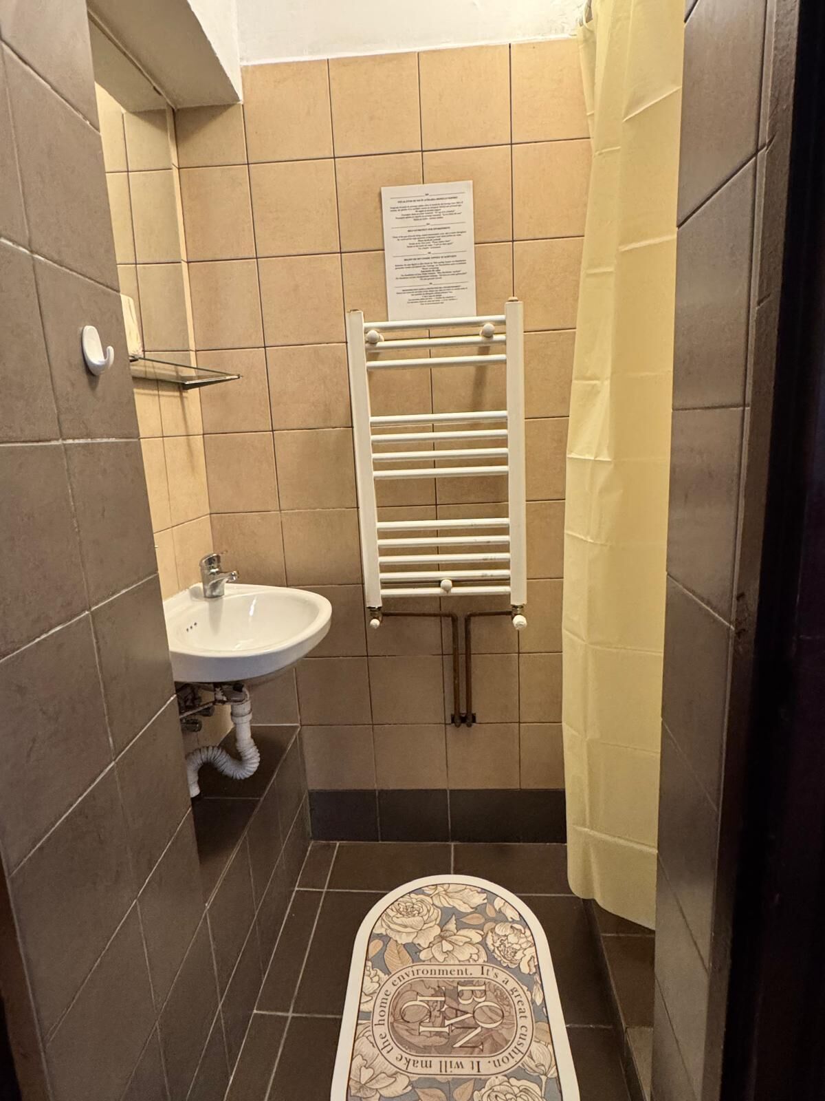 A small bathroom with a sink, towel rack, and a shower curtain.
