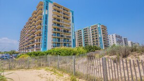 Un hôtel situé en bord de mer, avec plusieurs étages, des balcons et une plage de sable.