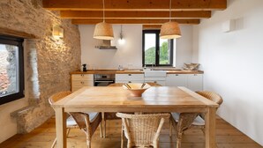 Una cocina rústica con vigas de madera, pared de piedra y un ventanal grande.